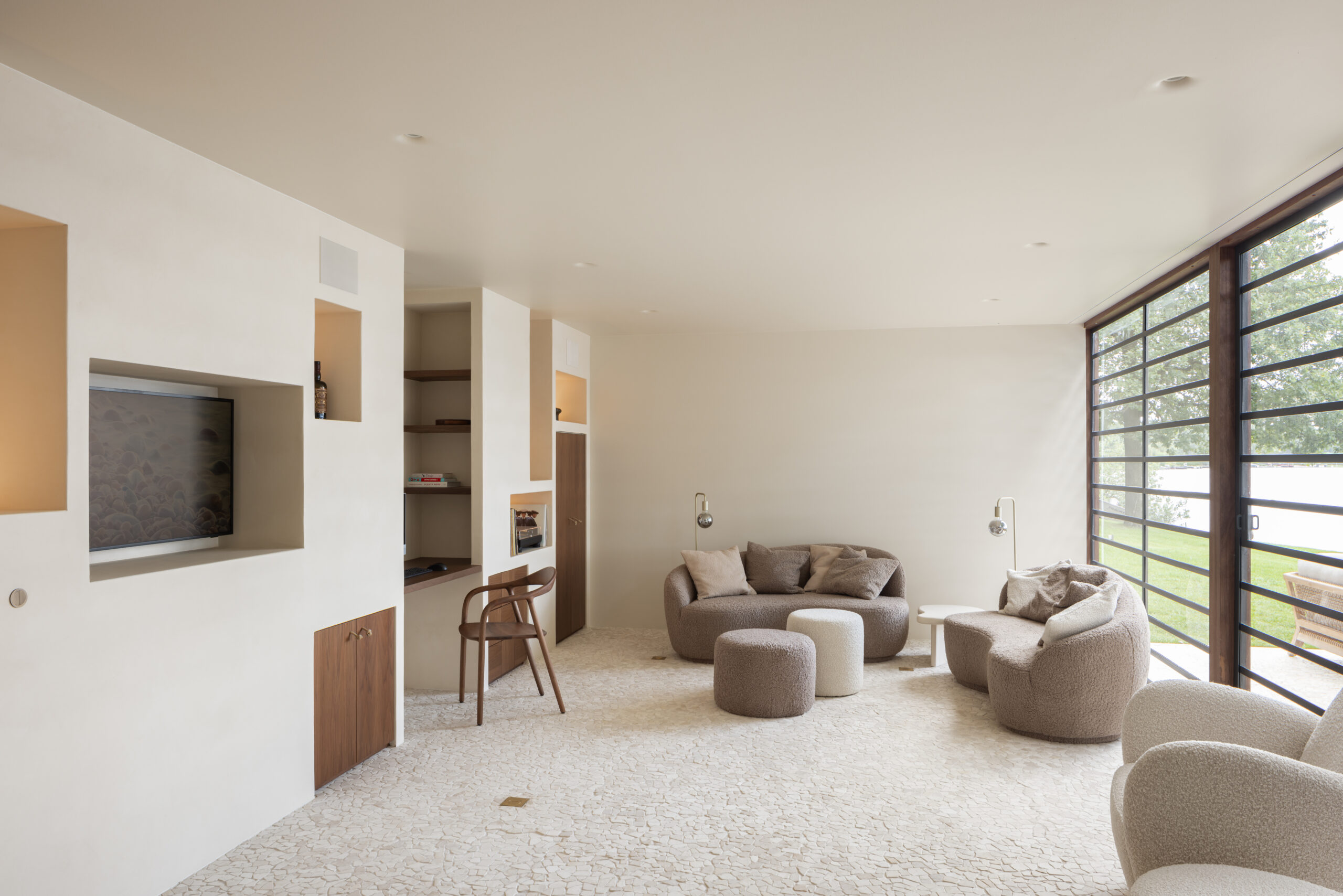 Maatwerkinterieur met geïntegreerde tv-wand, thuiswerkplek, verlichte nissen en walnoothouten accenten.